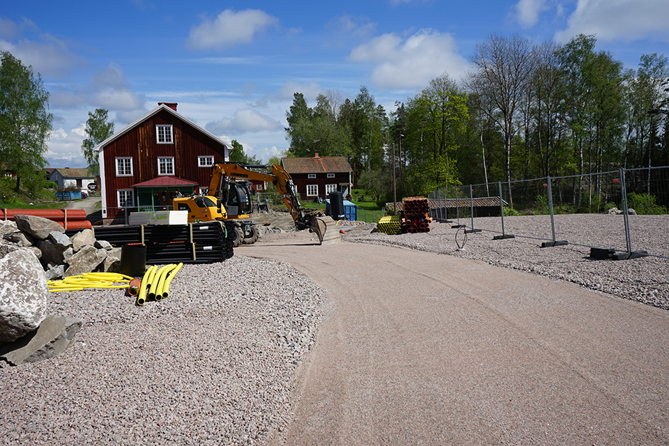 Foto över grusplanen nedanför Knektschaktet framför Vandrarhemmet, arbete  med att täcka marken med grus pågår